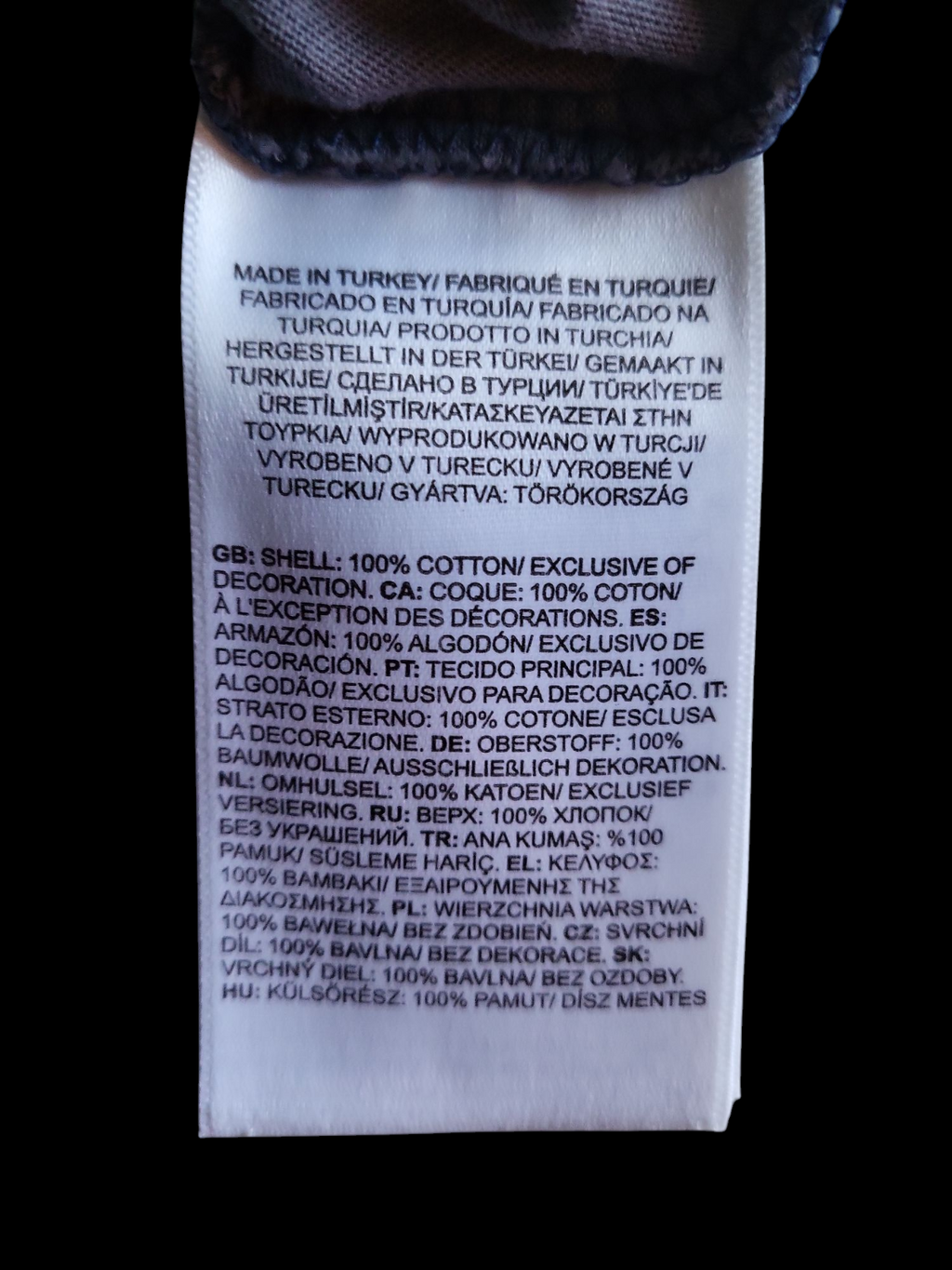 Clothing care label stating shell is 100% cotton, made in Turkey, multilingual text