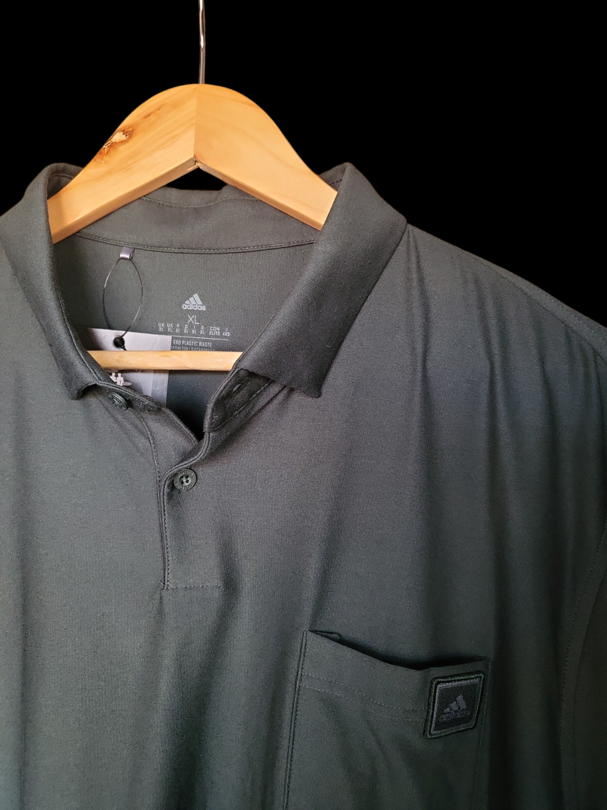 Black Adidas men's polo shirt with chest pocket on wooden hanger