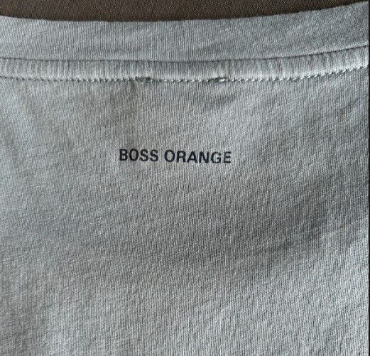 Close-up of BOSS ORANGE logo on light grey designer t-shirt collar for men