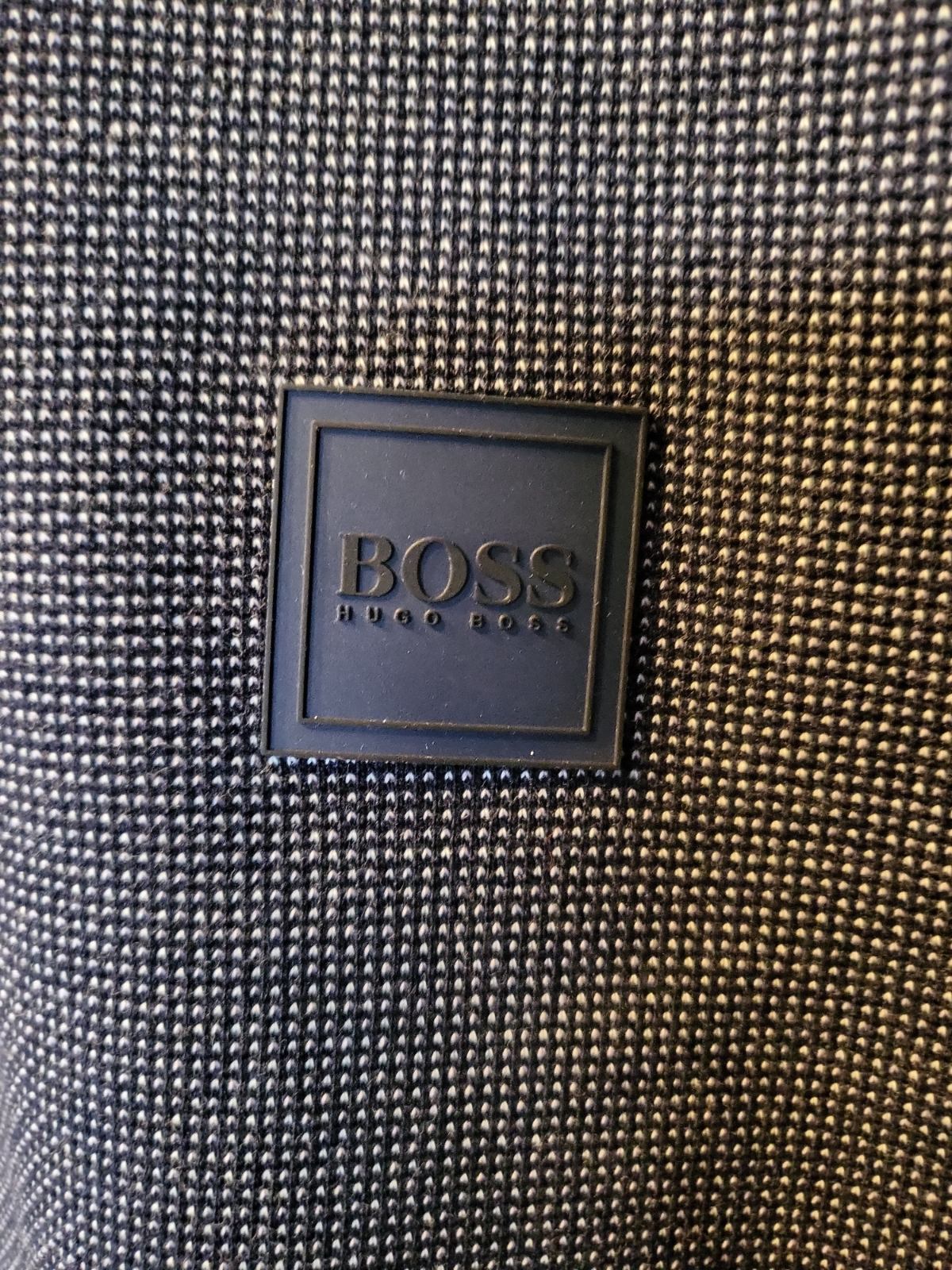 Textured black and white woven fabric with a square embossed BOSS logo patch