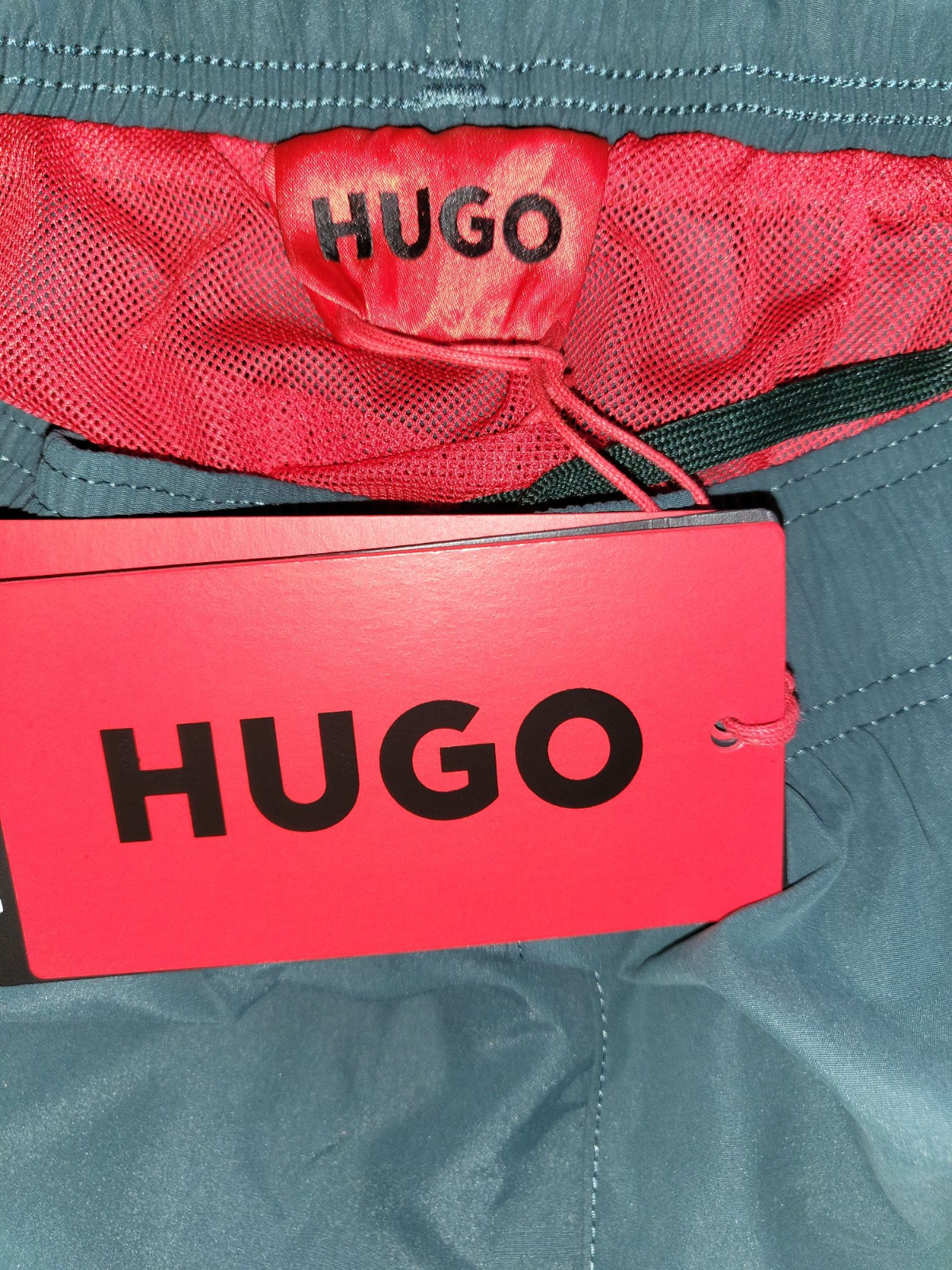 HUGO mens designer swim shorts with red mesh lining and branded tag