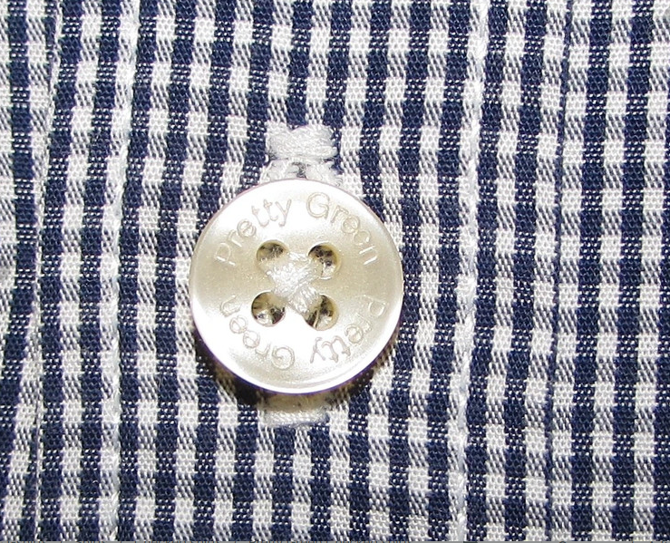 Pretty Green branded button on a navy and white checkered shirt fabric