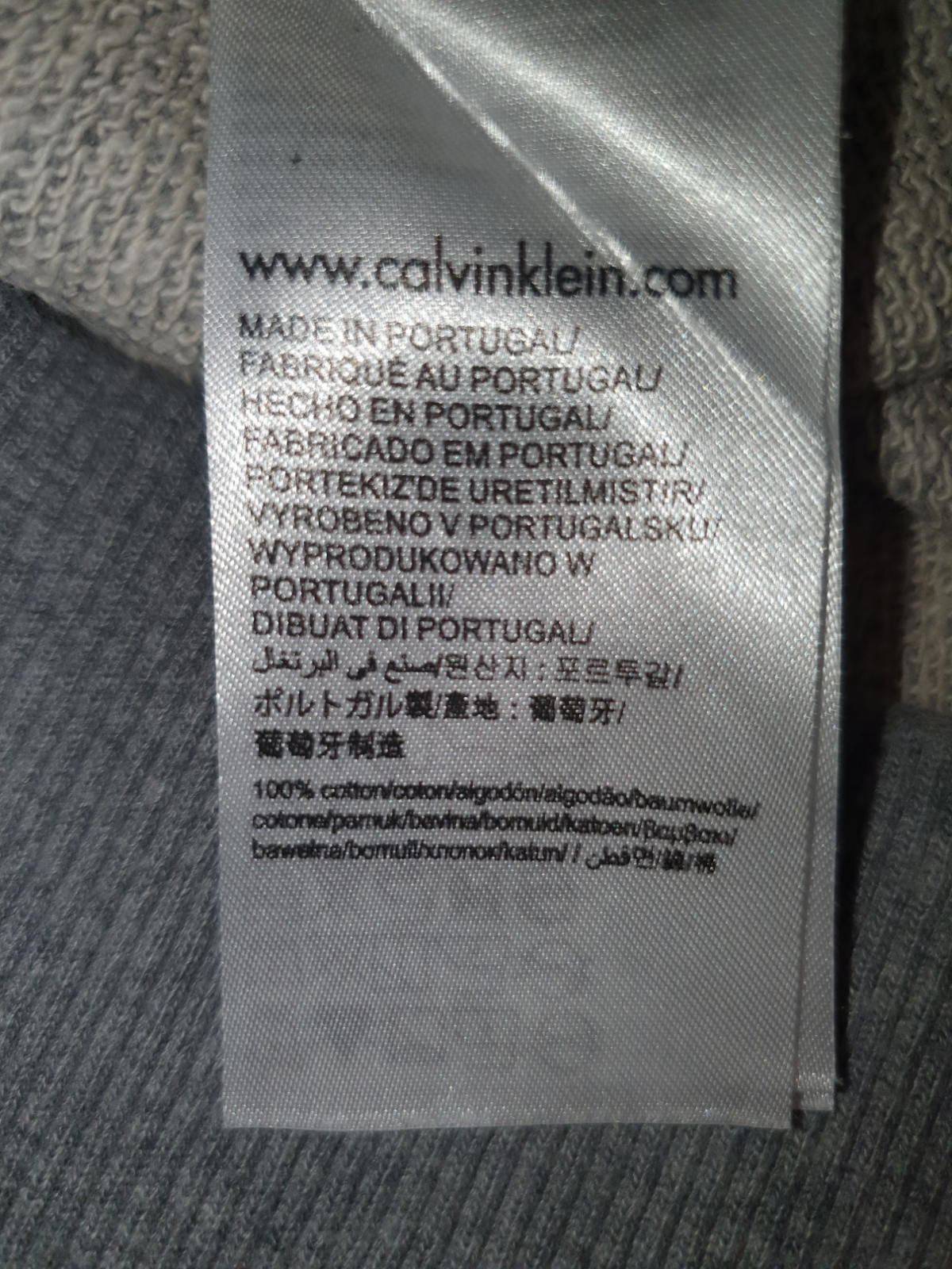 Clothing label showing www.calvinklein.com, made in Portugal, 100% cotton, multiple languages