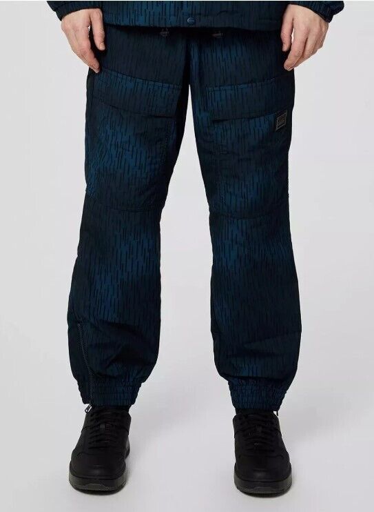 Men's dark blue patterned cargo pants with elastic cuffs, front pockets, and black sneakers