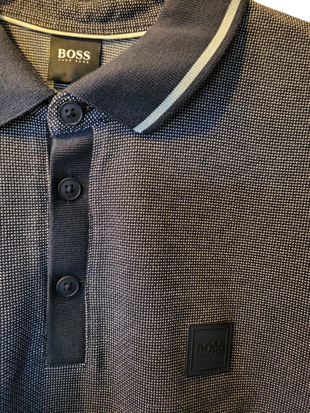 Close-up of textured navy designer polo shirt with white stripe collar and button placket