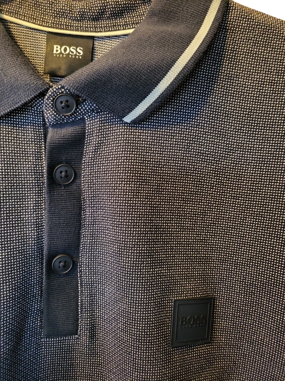 Close-up of textured navy designer polo shirt with white stripe collar and button placket