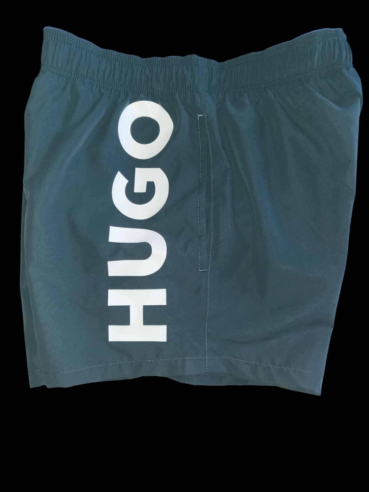 Black designer men's swim shorts with bold white HUGO logo and elastic waistband